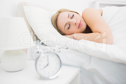 Alarm clock with focus on woman sleeping in bed