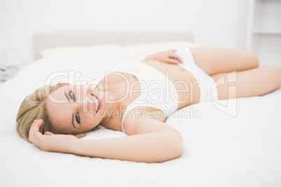 Smiling woman in undergarments lying in bed