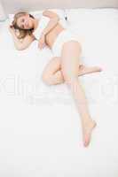 Portrait of woman in undergarments lying in bed