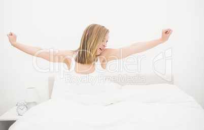 Sleepy woman yawning while stretching her arms in bed