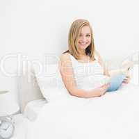 Portrait of happy woman reading book in bed