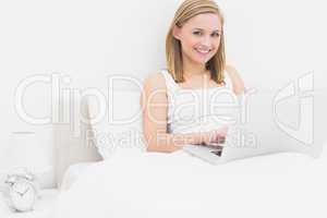 Portrait of happy relaxed woman using laptop in bed