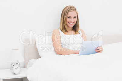 Portrait of smiling woman using digital tablet in bed