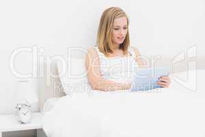 Woman using digital tablet in bed