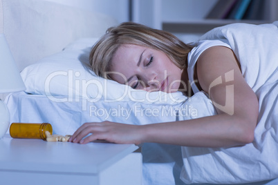 Asleep woman and spilt bottle of pills in bedroom
