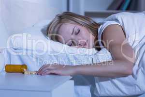 Asleep woman and spilt bottle of pills in bedroom