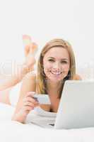Portrait of woman doing online shopping in bed