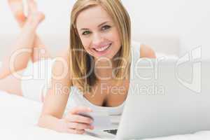 Portrait of woman doing online shopping in bed