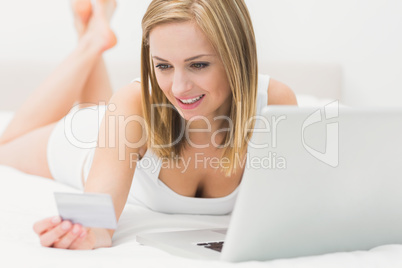 Casual young woman doing online shopping in bed