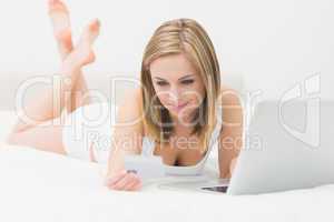 Casual young woman doing online shopping in bed