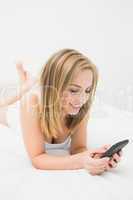 Casual woman with smartphone in bed