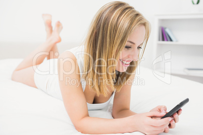 Casual young woman with smartphone in bed