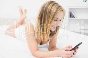Casual young woman with smartphone in bed