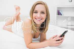 Portrait of casual woman with smartphone in bed