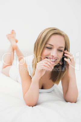 Casual young woman using mobile phone in bed