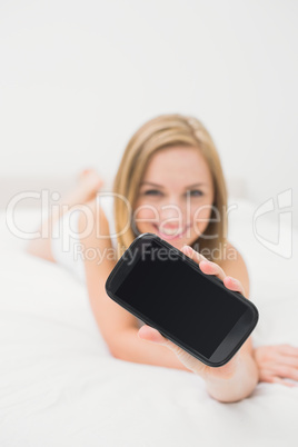 Woman showing you her new smartphone in bed