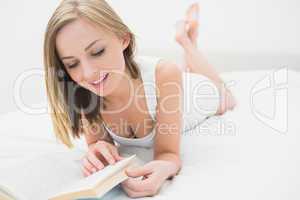 Young woman reading book in bed