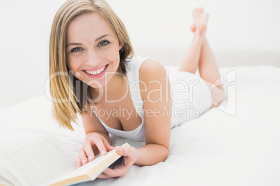 Portrait of young woman reading book in bed