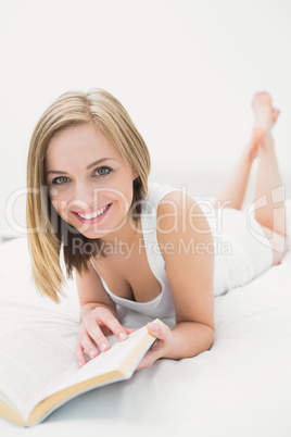 Portrait of young woman reading book in bed