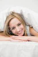 Close-up portrait of beautiful woman under sheet in bed