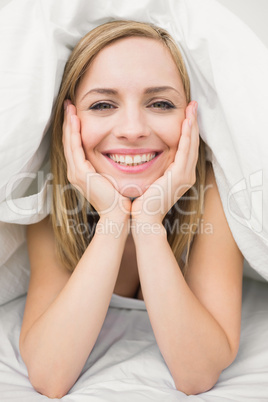 Close-up portrait of beautiful woman under sheet in bed