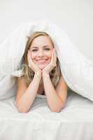 Portrait of beautiful woman under sheet in bed