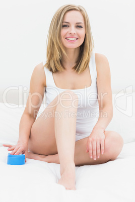 Portrait of woman sitting on bed with cream