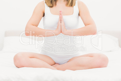 Woman sitting in praying position on bed