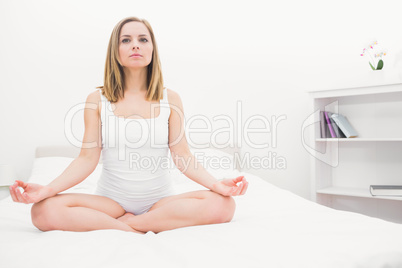 Woman sitting in lotus position on bed