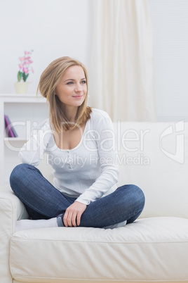 Casual thoughtful woman sitting on sofa