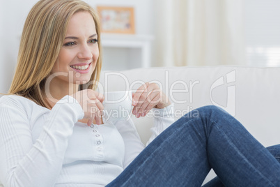 Woman with coffee cup day dreaming on couch