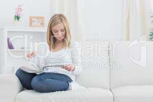 Casual young woman reading magazine at home