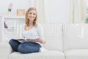 Portrait of happy woman with magazine at home