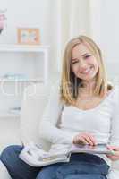 Portrait of happy woman with magazine at home