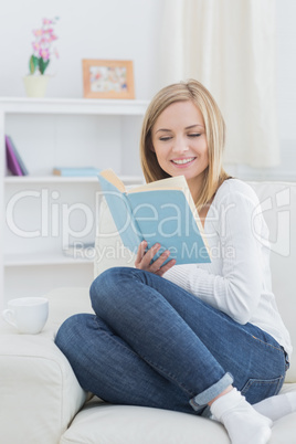 Happy young woman reading storybook at home