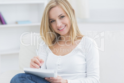 Young woman with notepad and pen at home Young woman with notepad and pen at home