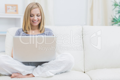 Relaxed happy woman using laptop on sofa