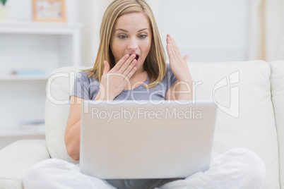 Surprised casual woman using laptop at home