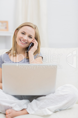 Portrait of casual woman using laptop and cellphone at home