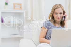 Casual woman using laptop and cellphone at home