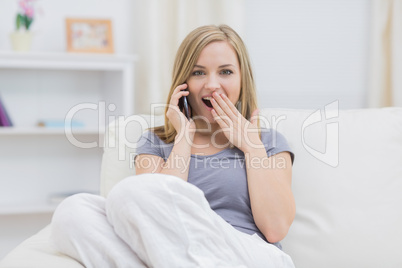 Portrait of surprised woman using cellphone at home