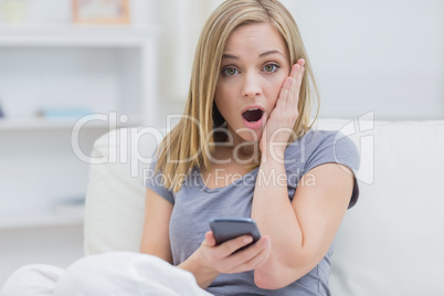 Portrait of casual shocked woman with cellphone at home Portrait of casual shocked woman with cellphone at home