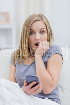 Portrait of casual shocked woman with cellphone at home