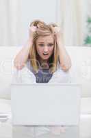 Frustrated casual woman with head in hands in front of laptop at
