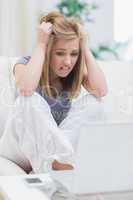 Frustrated casual young woman looking at  laptop screen