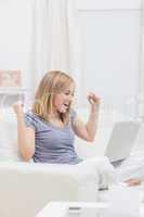 Excited casual woman with laptop at home