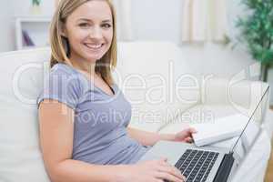 Casual woman with laptop and book in living room