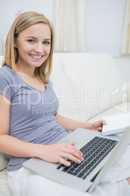 Casual woman with laptop and book in living room