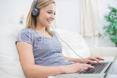 Woman listening music through headphones while using laptop