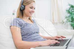 Woman listening music through headphones while using laptop